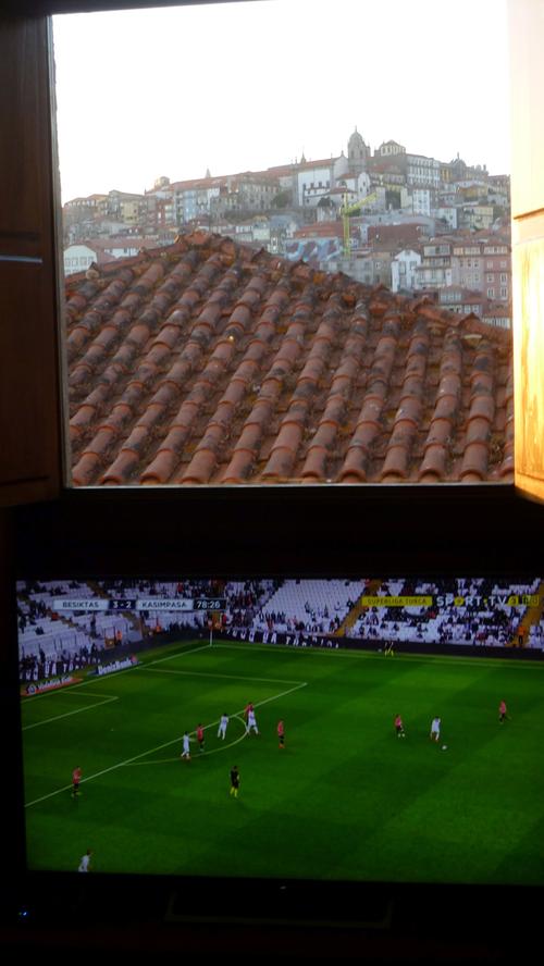 In der historischen Portweinfabrik von Sandemann in Porto befindet sich ein Hostel. Hier wird im Speisesaal gerade ein Fußballspiel im Fernsehen gezeigt, während das Fenster über dem Apparat der Blick auf die Altstadt eröffnet.