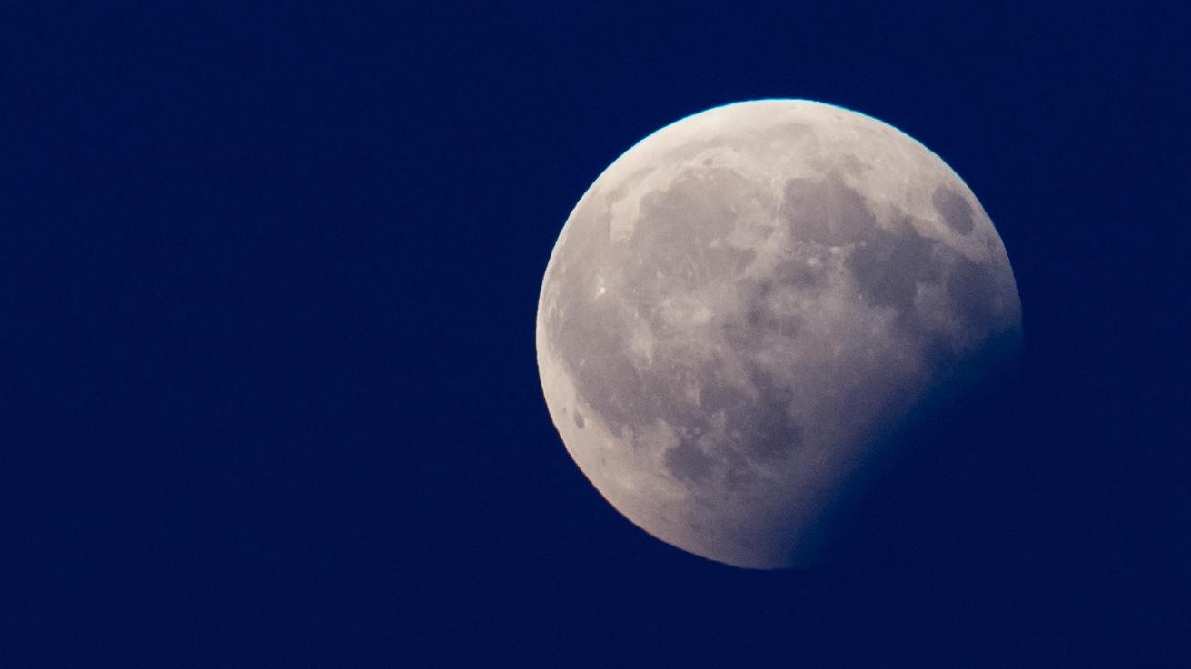 Bei einer partiellen Mondfinsternis verdunkelt sich der Mond teiweise, weil er durch den Erdschatten wandert.