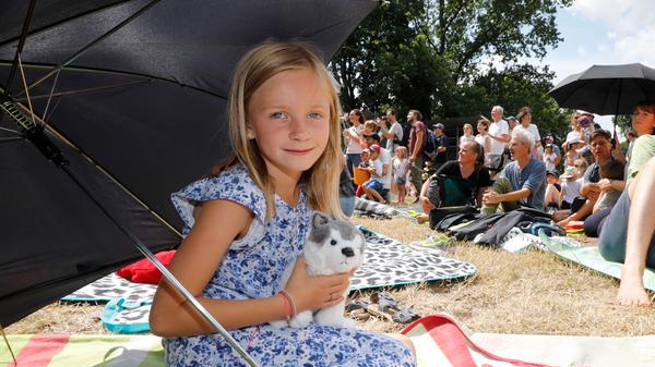 Viele zogen sich ganz unter schattige Bäume zurück, aber Amelie hatte zum Glück einen großen Schirm mitgebracht. Der half nach dem Ende des Familienkonzerts auch gegen den Wolkenbruch.