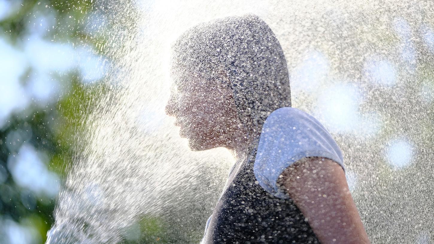 Da hilft nur noch Abkühlung: Ein Mädchen erfrischt sich in Nürnberg mit einem Wasserschlauch.