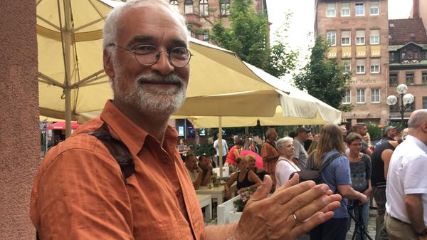 Thomas Wrensch (62): "Ich bin fast jedes Jahr hier. Das was ich gestern und heute mitbekommen habe, gefällt mir gut: Schöne, vielfältige Musik. Das Bardentreffen passt immer gut zum Ferienanfang. Ich habe auch drei Kinder dabei. Die sitzen hier vorne in der ersten Reihe und schauen ganz gebannt zu. Das ist Kultur in der Basis. Ich finde es schön, dass sich Nürnberg als Kulturhauptstadt 2025 bewirbt. Ich bin gespannt, was das für Auswirkungen auf das kulturelle Leben in Nürnberg hat."