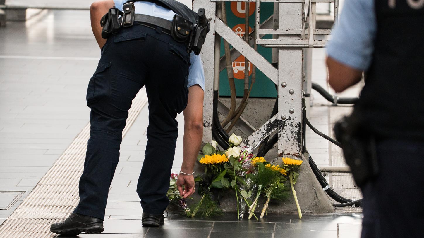 Ein Polizist legt nach der Attacke im Frankfurter Bahnhof Blumen nieder.
