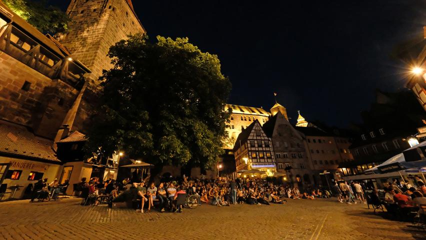 Der Tiergärtnertorplatz ist ein besonderer Treffpunkt in der Altstadt - vor allem, wenn es dunkel wird. Viele Scheinwerfer illuminieren die Gebäude, die Kopfsteine, aber auch die Kaiserburg im Hintergrund - bis Mitternacht.