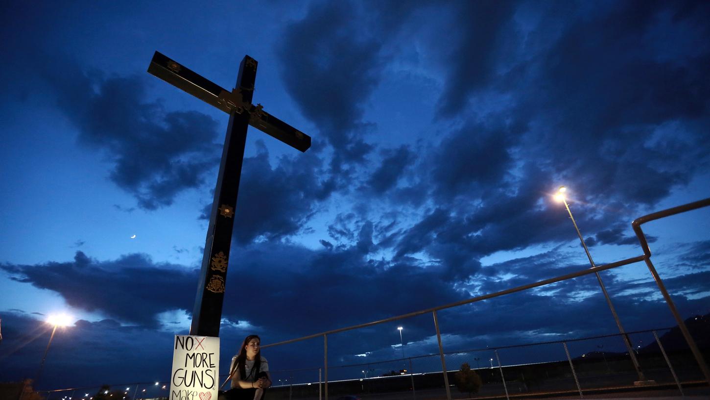 Eine Frau sitzt neben einem Schild mitder Aufschrift" No more Guns, make Love" nachdem ein Schütze in einem Einkaufszentrum in El Paso, im US-Bundesstaat Texas, mindestens 20 Menschen getötet und mindestens 26 weitere verletzt hatte.