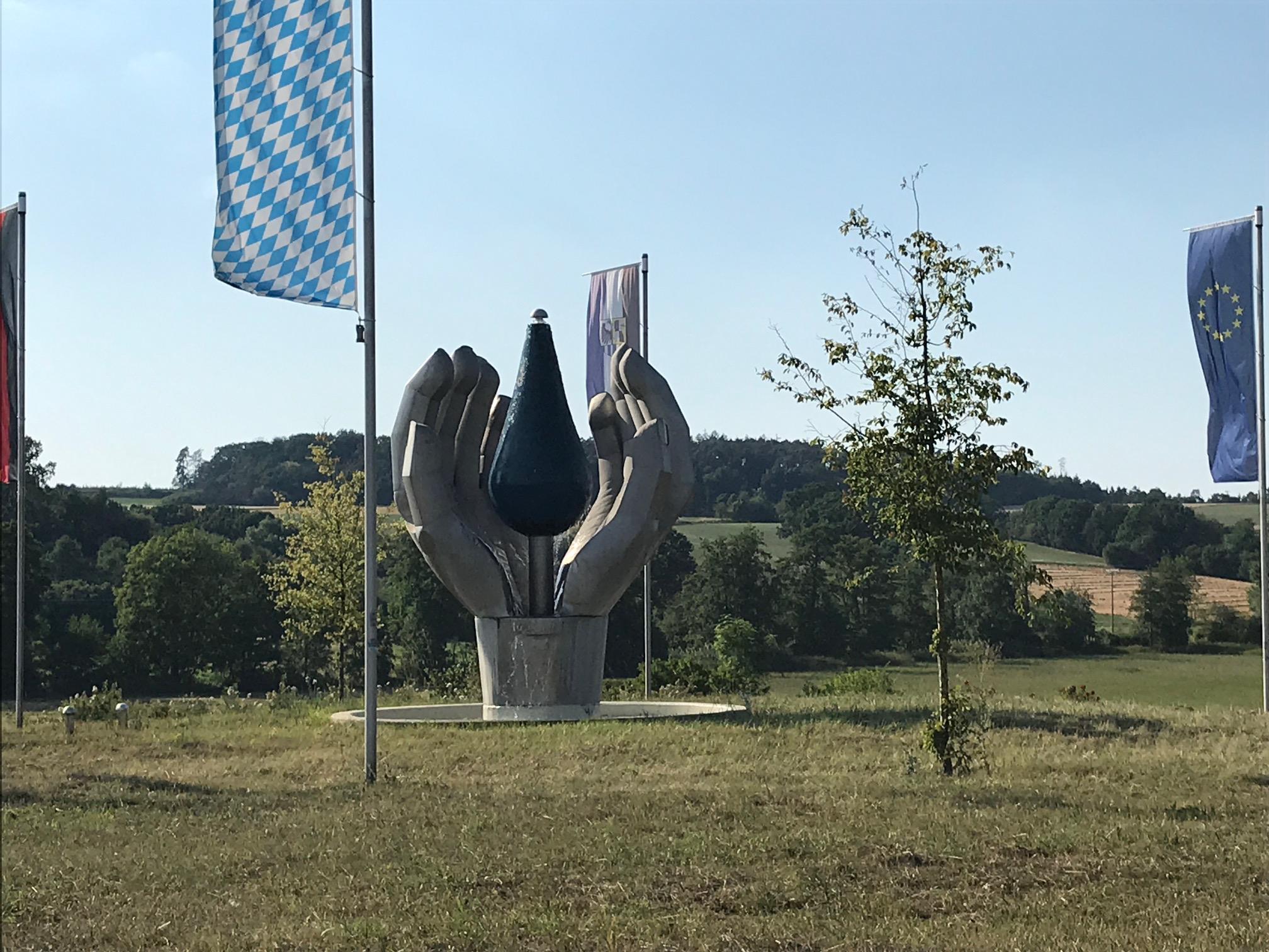 Und noch ein Kunstbrunnen: Dieser steht in der Mitte des Kreisverkehrs zwischen Neustadt an der Aisch und Diespeck. Seine Gestaltung mit Händen, die einen Wassertropfen halten, hat nicht nur zufällig etwas mit dem in unmittelbarer Nachbarschaft des Kreisverkehrs angesiedelten Mineralwasserabfüller zu tun.