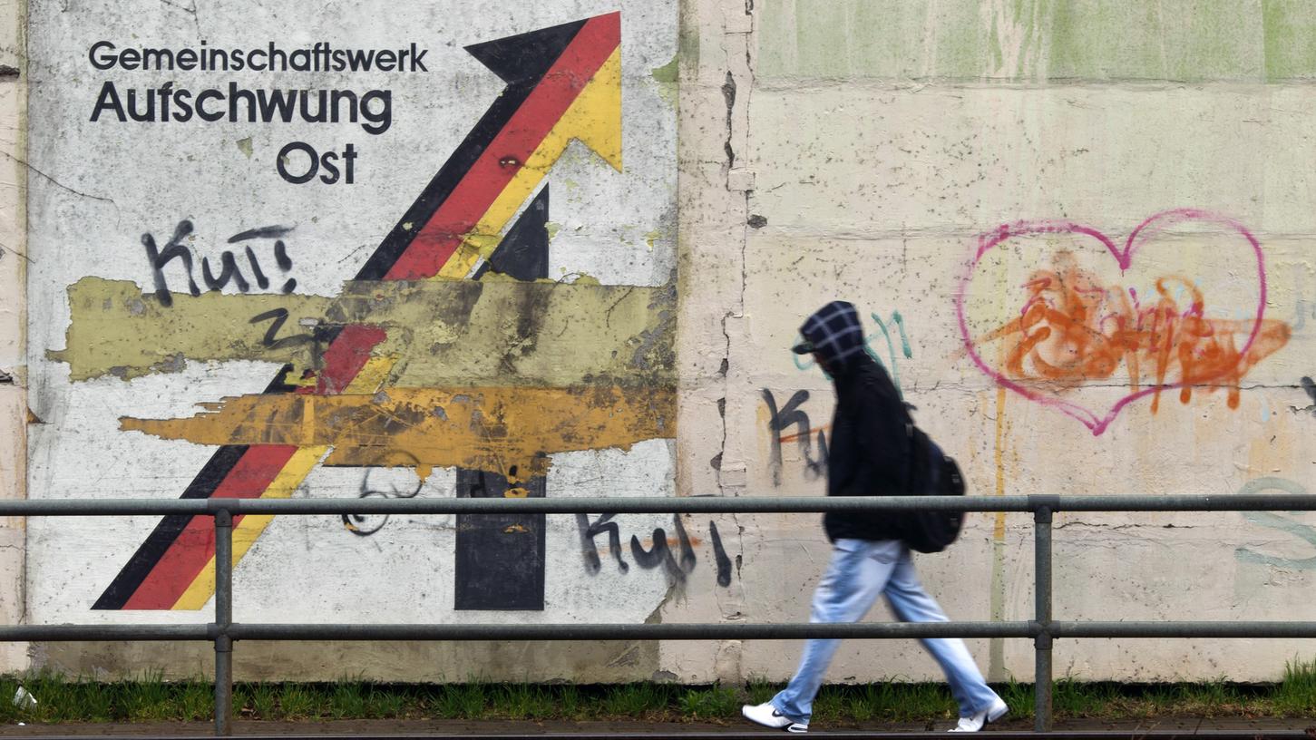Ein Mann geht in Magdeburg an einem Wandbild aus der Wendezeit vorbei. Fast 30 Jahre nach der Einheit entzweit der Streit um den Solidaritätszuschlag die Große Koalition.