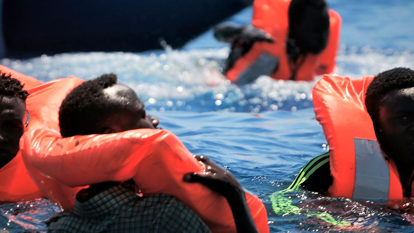 Migranten schwimmen mit Rettungswesten im Meer, bevor sie auf das Rettungsschiff der Hilfsorganisationen SOS Méditerranée und Ärzte ohne Grenzen "Ocean Viking" aufgenommen werden.