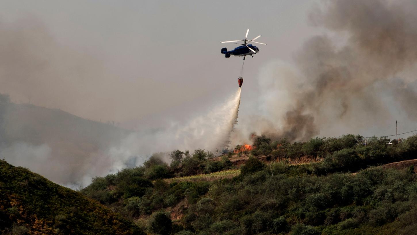 Ein Hubschrauber versucht mit Wasser ein Feuer auf Gran Canaria zu löschen.