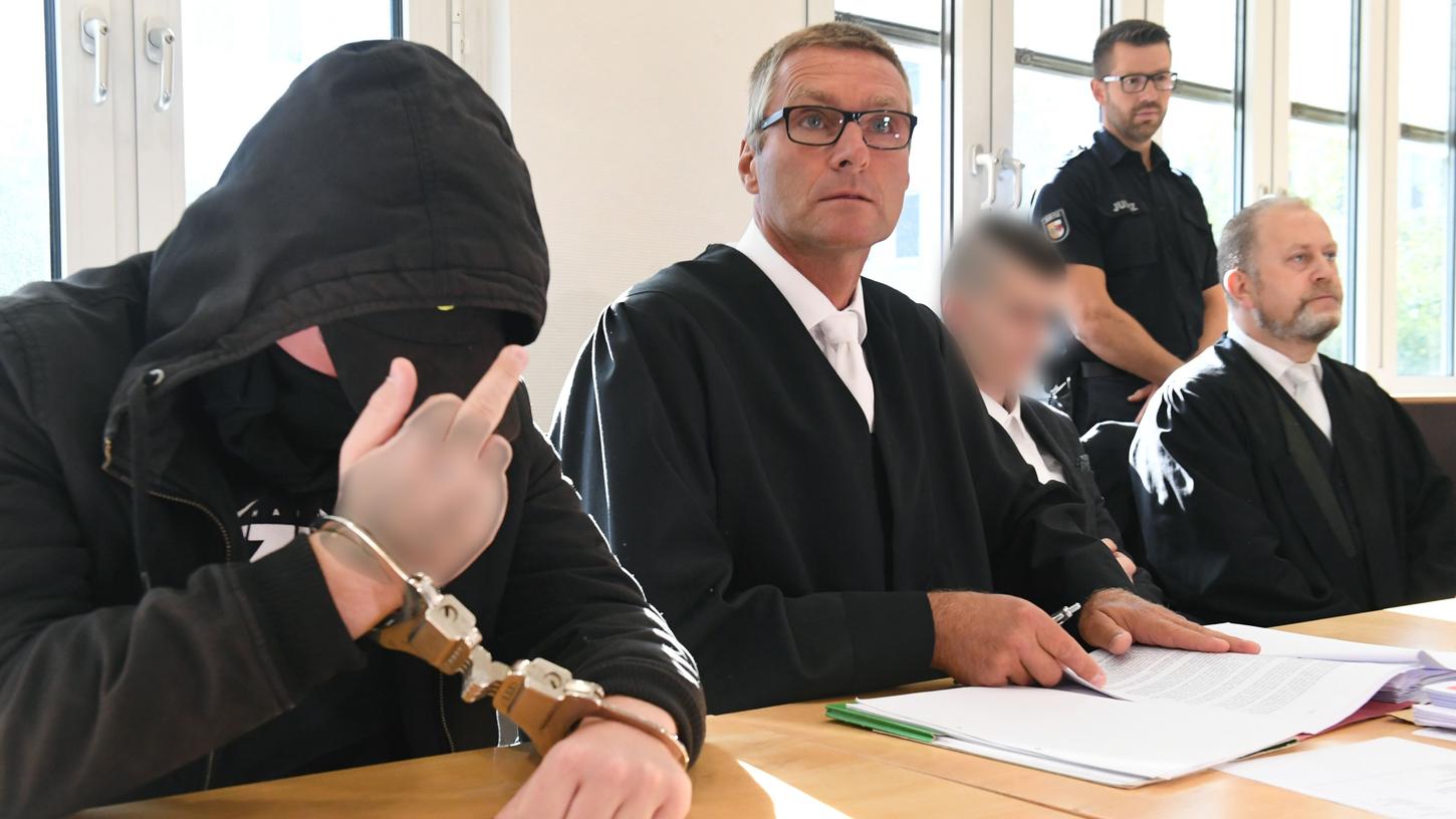 Der 19-jährige Angeklagte zeigt im Gerichtssaal im Landgericht den Mittelfinger. Für den Mord an der 18-jährigen Maria aus Zinnowitz auf Usedom müssen sich am selben Tag der 19- und ein 21-Jähriger (3.v.l.) vor dem Gericht verantworten.