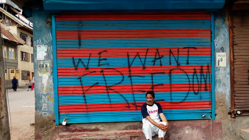 "Wir wollen Freiheit" steht als Graffito auf der Ladenfront dieses Mannes in Srinagar in der Provinz Kaschmir. Viele Menschen in der Region wehren sich derzeit dagegen, dass die indische Zentralregierung die Provinz wieder enger kontrollieren möchte. Kaschmir ist seit Jahrzehnten ein Konfliktherd zwischen den beiden Atommächten Indien und Pakistan.