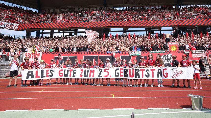 Vor dem Spiel geht der Blick in die Nordkurve: Die Ultras Nürnberg feiern 25-jähriges Jubiläum - und freuen sich über die Glückwünsche der Mini-Cluberer.