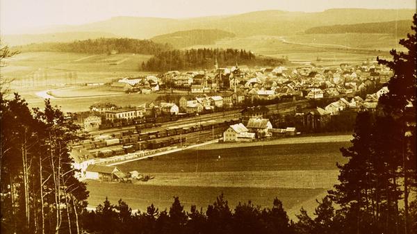 Die Eisenbahn brachte dem Knotenpunkt Treuchtlingen wirtschaftlichen Aufschwung und überregionale Bedeutung. Zeitweise war sie mit über 1000 Mitarbeitern der größte Arbeitgeber der Region, die Einwohnerzahl der Stadt vervielfachte sich. Unser historisches Foto zeigt links den Bahnhof (noch ohne das 1906 deutlich vergrößerte Bahnbetriebswerk), dahinter die Altmühl und im Vordergrund die Bäume am Hang des noch unbebauten Patrichbergs/Grüntäleins.