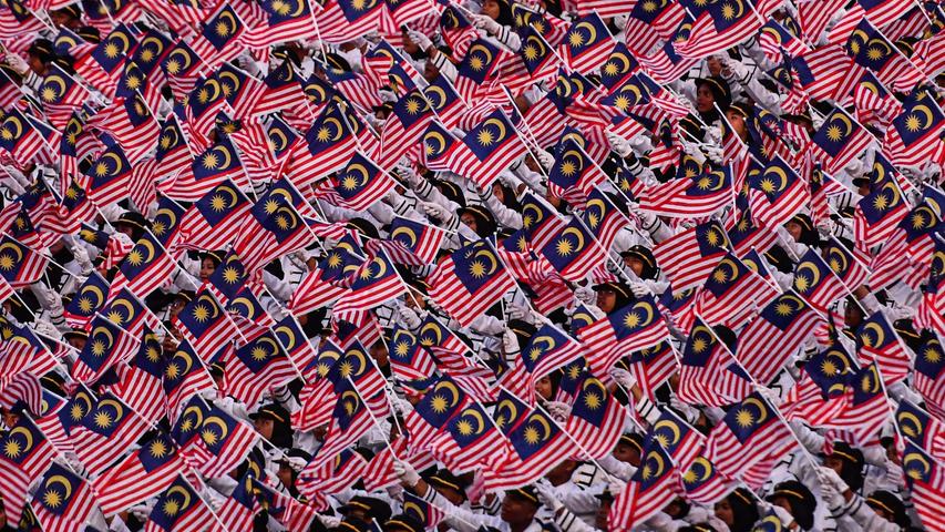 Malaysische Schulkinder schwenken Nationalflaggen während einer großen Parade anlässlich des Nationalfeiertags. Am Freitag feierte die konstitutionelle Monarchie in Putrajaya, dem Verwaltungssitz von Malaysia, den 62. Jahrestag ihrer Unabhängigkeit. Einst war diese Region eine britische Kolonie.