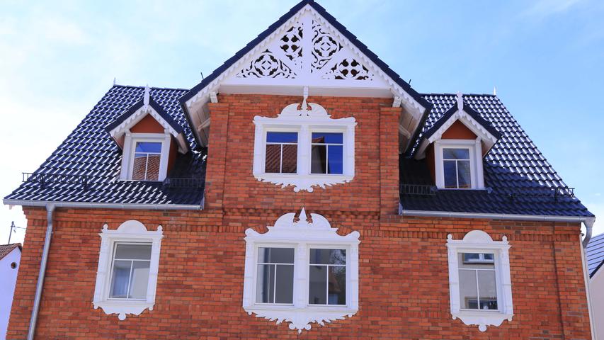 Er zeigt einen zweigeschossigen Satteldachbau mit Zwerchhaus aus Backstein. Im Obergeschoss fallen die weißen, hölzernen und pittoresken Fensterumrahmungen auf.