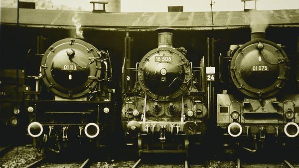 Drei Schnellzuglokomotiven der Baureihen 18 (Baujahre 1901-1938, zunächst Königlich Bayerische Staatseisenbahn, später Deutsche Reichsbahn) und 01 (1925–1938, zunächst Reichsbahn, später auch Deutsche Bundesbahn, rechts im Originalzustand, links modernisiert) vor dem Lokschuppen des Treuchtlinger Banhnbetriebswerks. Das Bild stammt aus den 1960er Jahren. Die Baureihe 18 wurde später mit einer Abschiedsfahrt von Lindau nach Treuchtlingen verabschiedet, wobei das damals noch existierende Bahnbetriebswerk (1870 erbaut, 1906 erweitert) von Eisenbahnfreunden "gestürmt" wurde, die dann aber recht enttäuscht waren, weil es schon so gut wie nichts mehr zu sehen gab.