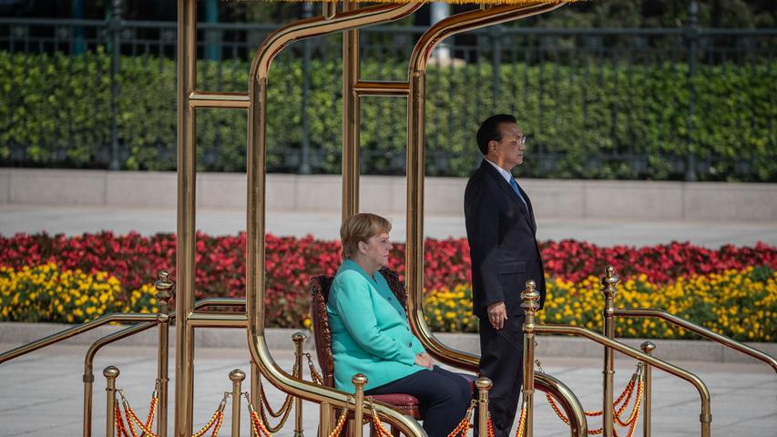 Bundeskanzlerin Angela Merkel besuchte schon zum zwölften Mal China. Diesmal war es wegen der Unruhen in Hongkong eine besonders heikle Visite. Der chinesische Premier Li Keqiang gibt sich jedoch überaus freundlich. Während die Nationalhymnen gespielt wurden, saß Merkel wieder. In den vergangenen Monaten machte sie das zu Hause wiederholt, weil sie im Stehen bei solchen Zeremonien anfing zu zittern. Premier Li stand aber bei der chinesischen Hymne auf.