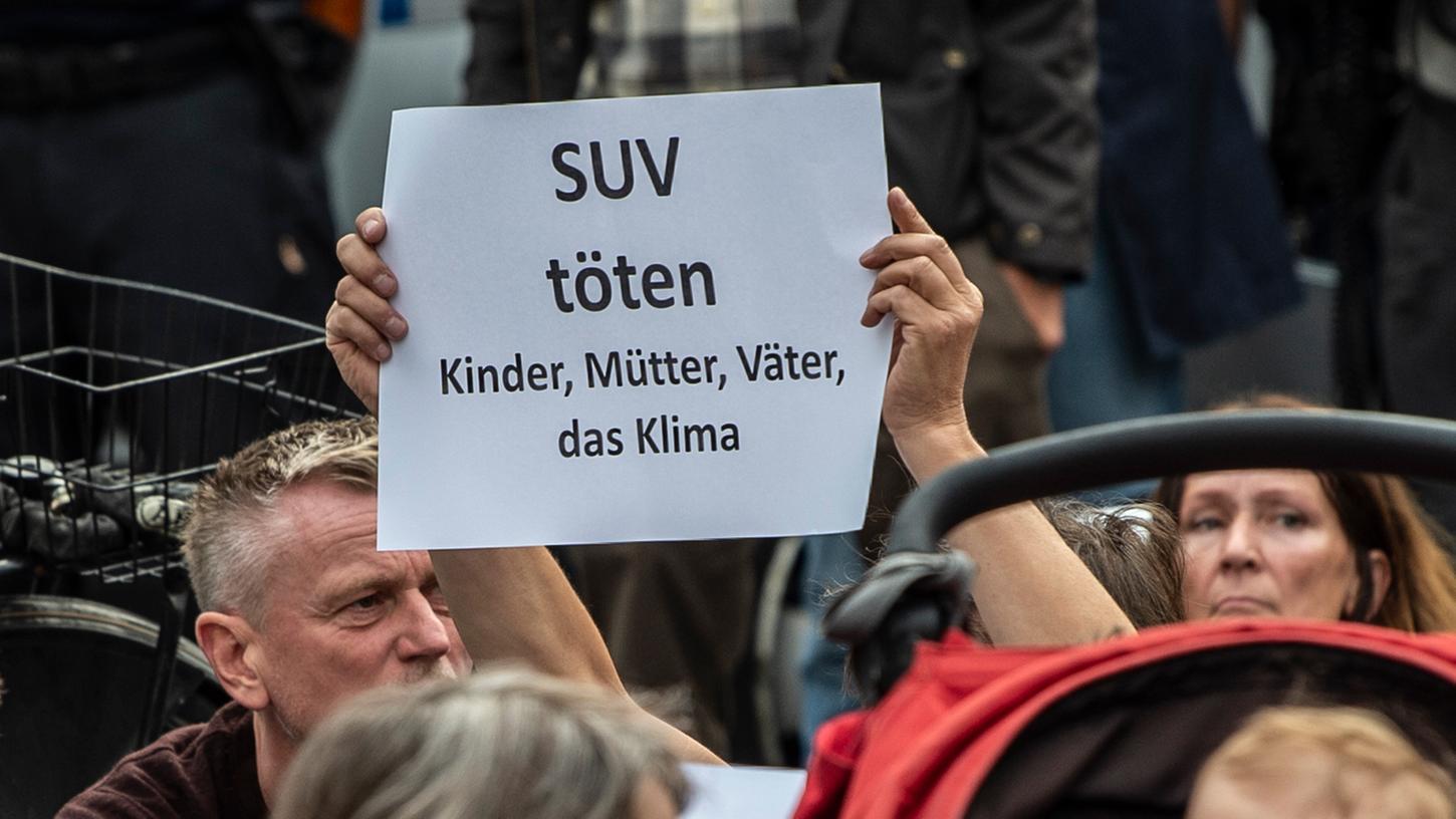 Ein Teilnehmer der Mahnwache, bei der der Verkehrstoten gedacht wird, stehen mit einem Schild an der Stelle, an der in Berlin vier Menschen bei einem Verkehrsunfall gestorben waren.