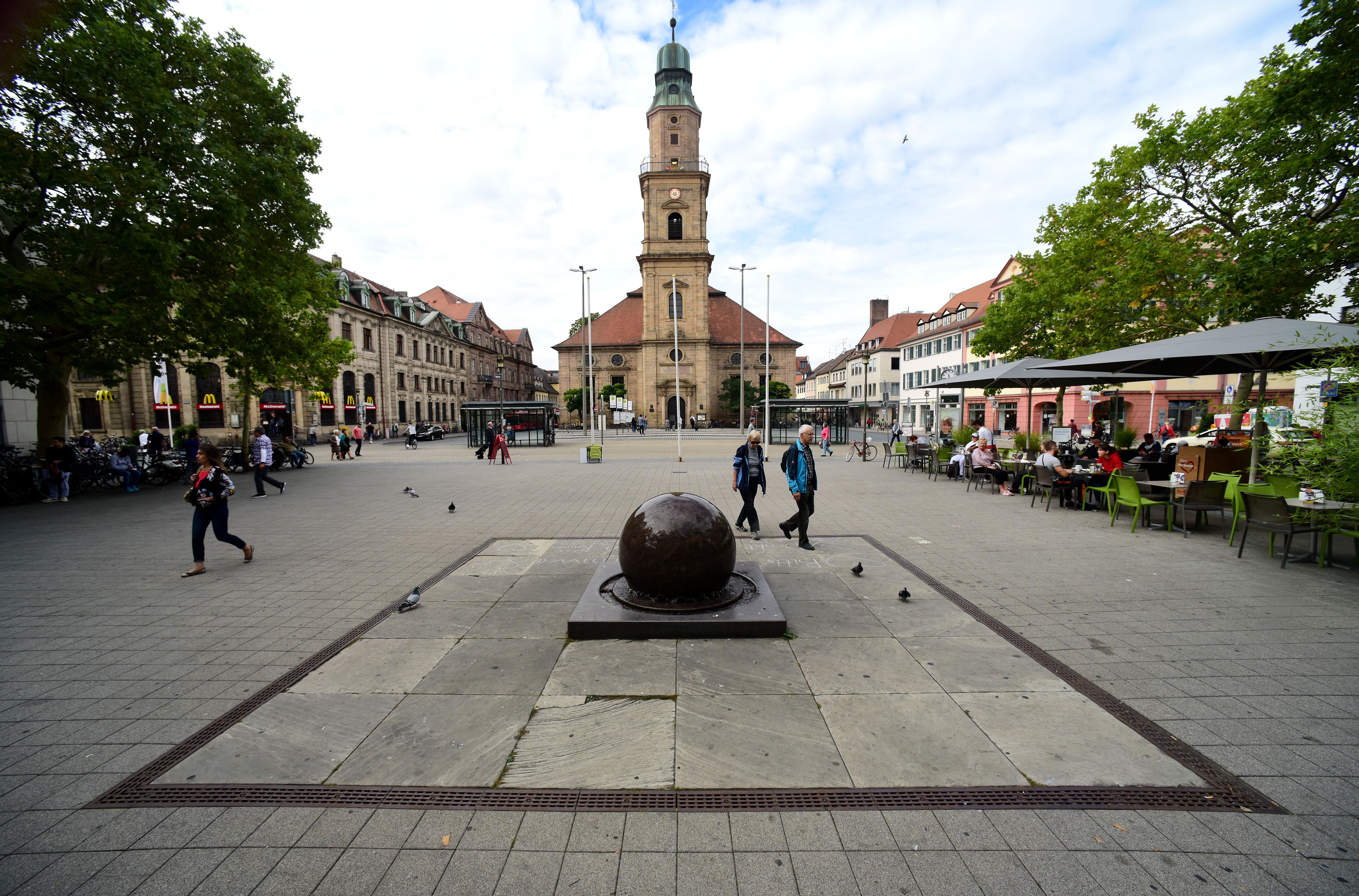 Der Kugelbrunnen am Hugenottenplatz mit Blick auf die Hugenottenkirche.
