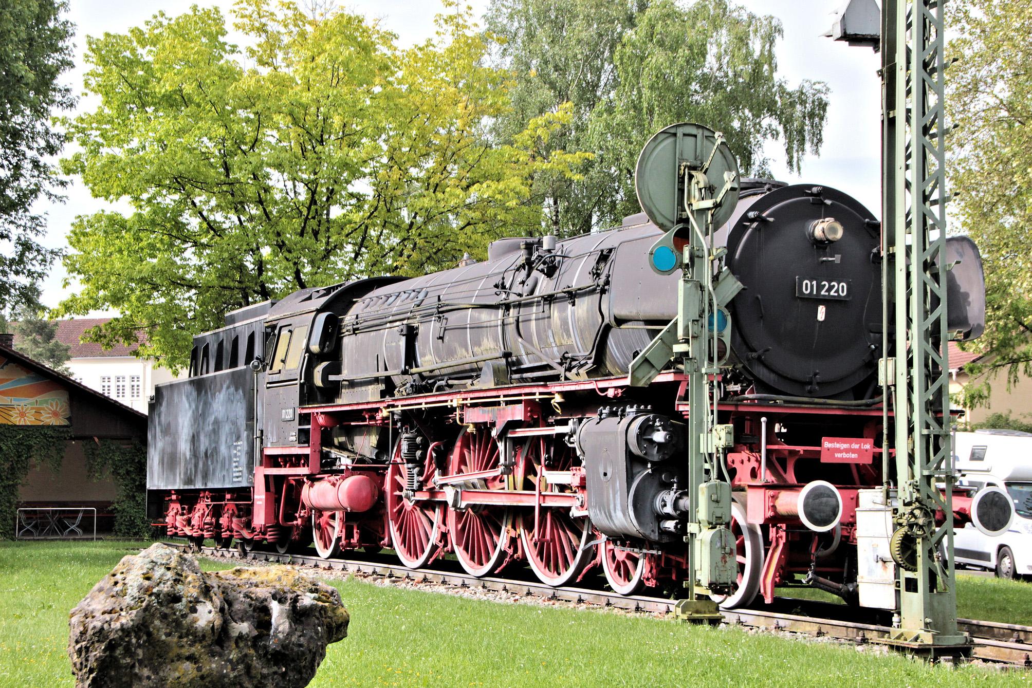 Die Treuchtlinger "Denkmalslok" vom Typ 01 220 aus dem Jahr 1937 wurde im Sommer 1969 zeitgleich mit der Schließung des Bahnbetriebswerks in der Grünanlage zwischen Schloss und Senefelder-Schule aufgestellt. Bevor sie hier ihren „Altersruhesitz“ fand, war die Dampflok im Betriebswerk saniert worden. 1989 und 2015 bekam sie nochmals einen neuen Anstrich.