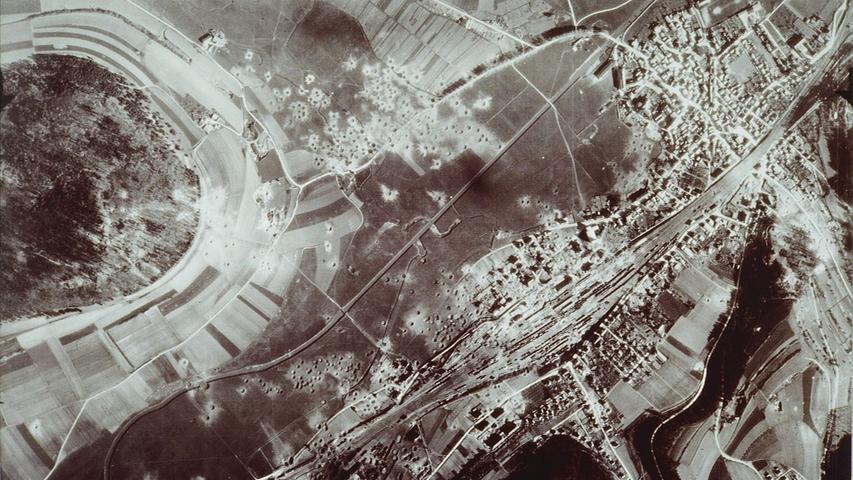 Ein Luftbild der Stadt Treuchtlingen und der zerstörten Bahnanlagen gegen oder kurz nach Ende des Zweiten Weltkriegs. Gut zu erkennen sind die vielen runden Bombenkrater entlang der Bahnlinie und an der Kästleinsmühle am Fuß des Nagelbergs (links).