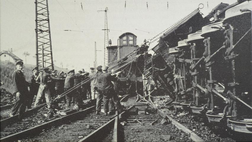 Männer versuchen mit Muskelkraft, eine im Treuchtlinger Bahnhof umgestürzte Dampf-Güterzuglokomotive vom Typ G12 (Lok 58 1823) wieder aufzurichten. Der Unfall passierte bei einer Flankenfahrt im Jahr 1939. Die G12 wurde zwischen 1917 und 1924 gebaut und 1953 ausgemustert (in der DDR erst 1976).