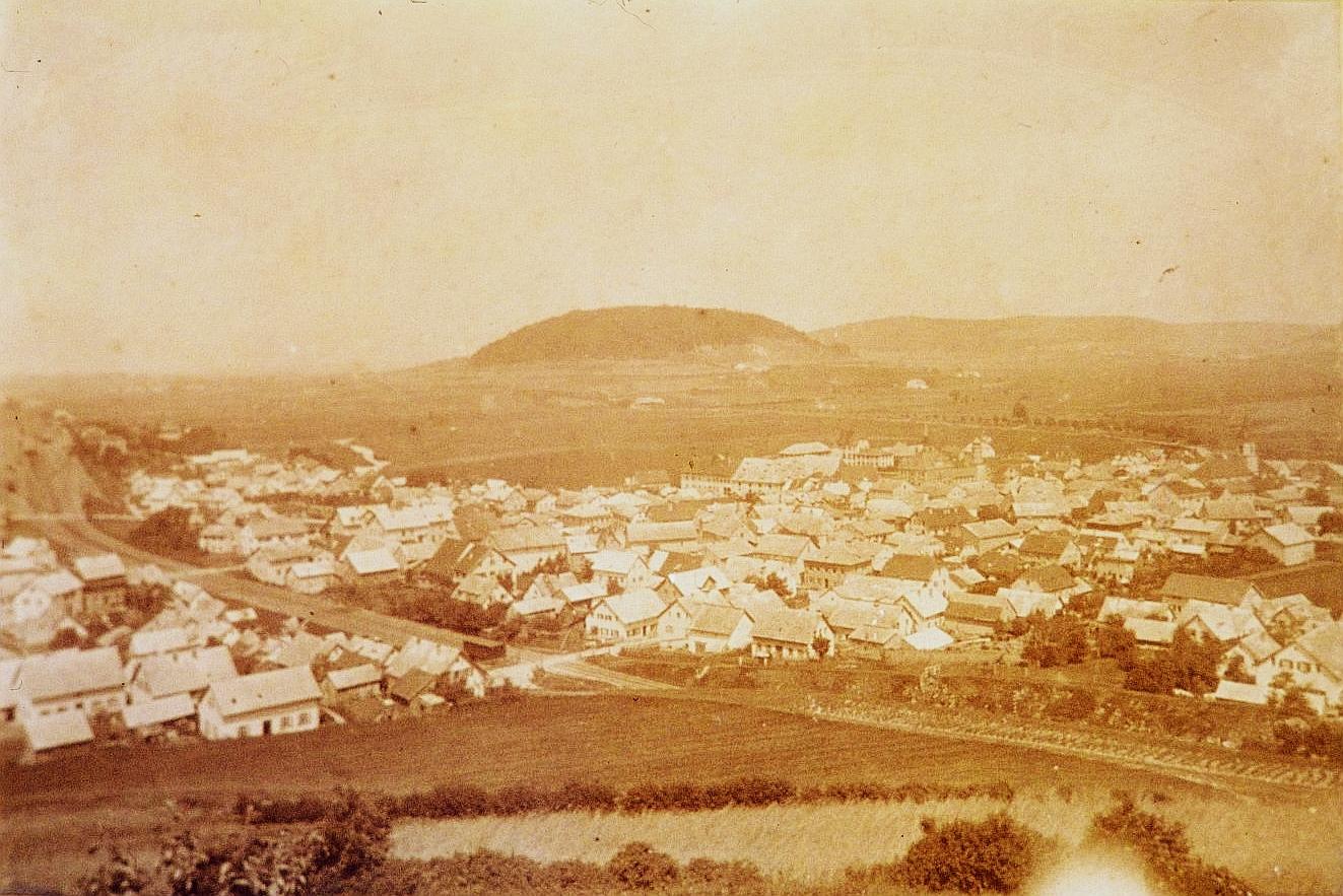 Im Herbst 1869 fuhr der erste Zug von Treuchtlingen über Weißenburg nach Pleinfeld. Das Bild zeigt den Verlauf der Trasse durch das damals noch winzige Treuchtlingen vom Perlachberg aus aufgenommen. Gut erkennbar sind die drei beschrankten Bahnübergänge (links, hell) - im Vordergrund unweit des heutigen Friedhofs und in der Mitte auf Höhe der heutigen Oettinger Straße. Unterführungen gab es erst später. Im Hintergrund ist der Nagelberg zu sehen und davor schwach erkennbar Schloss und Rathaus.