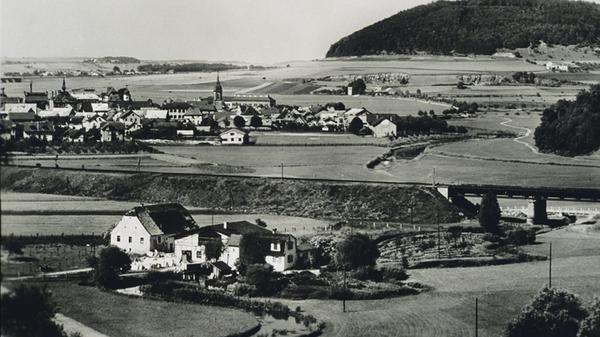 Dieses alte Bild zeigt die Bahnstrecke Treuchtlingen-Ingolstadt mit der Schmarrmühle im Vordergrund und der Möhrenbachbrücke (heutiger Standort der Kläranlage). Das Foto dürfte vor 1934 aufgenommen sein, da das Rathaus links im Bild noch reich verziert ist - 1934 wurde es von den Nazis zu einem Zweckbau umgebaut und der Uhrturm entfernt. In der Bildmitte ist allerdings schon der langgestrecke Giebel des Reichsarbeitsdienst-Lagers erkennbar, im Hintergrund der Nagelberg.