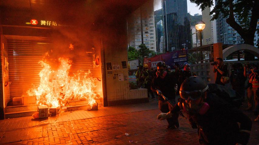 Während Zusammenstößen zwischen Protestierenden und der Polizei in Hongkong rennen Demonstranten an einem Feuer vorbei. Seit Wochen protestiert die Bevölkerung in Hongkong gegen die Regierung.