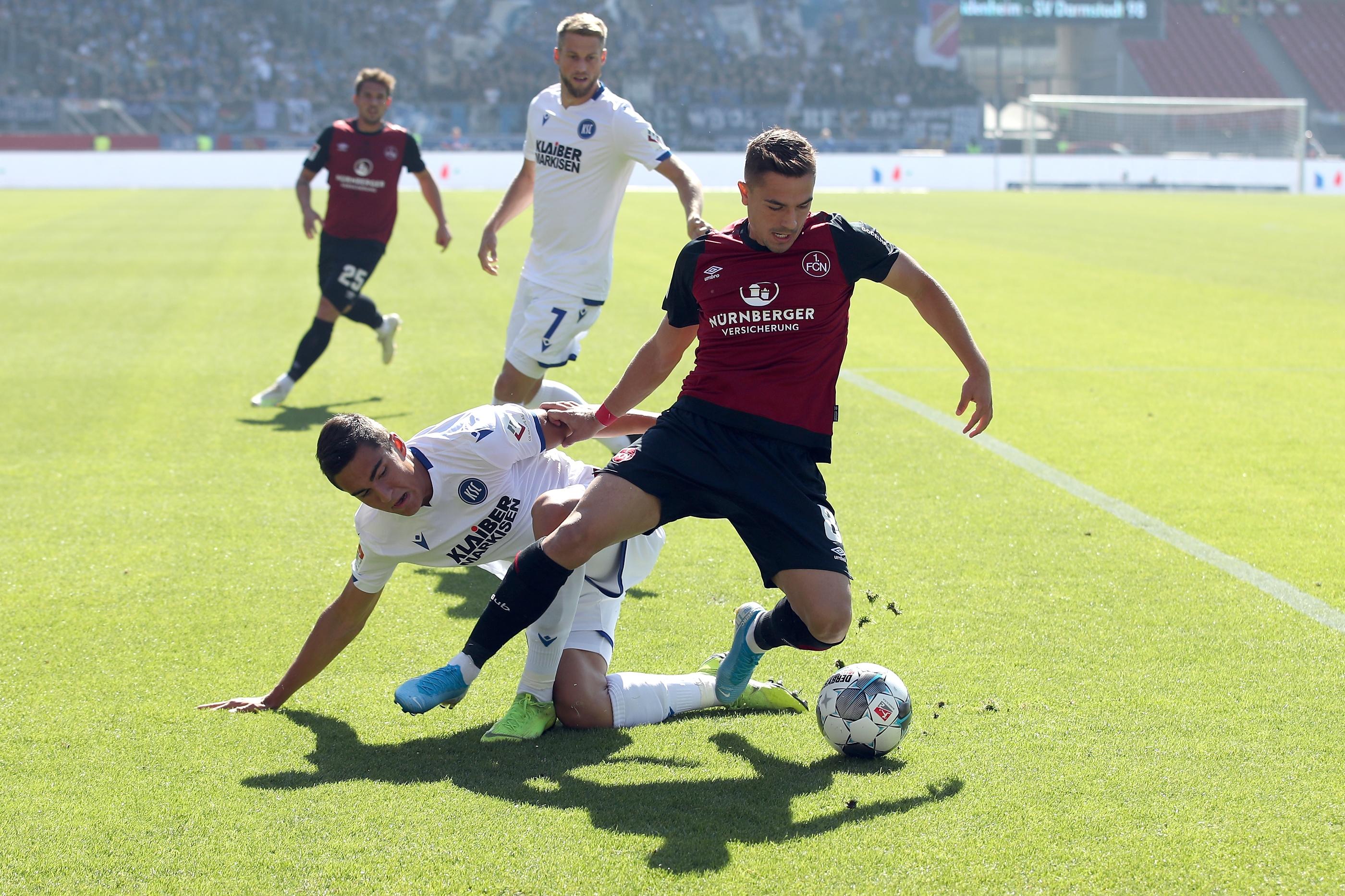 Rein in die Partie! Der Club, der gegen Heidenheim und in Darmstadt jüngst dreifache Punktgewinne verschludert hatte, tut sich in einer hektischen Anfangsphase gegen dicht gestaffelte Badener schwer, eine Lücke zu finden. Auffällig beim Altmeister ist in dieser Phase eigentlich nur der quirlige Nikola Dovedan, der auf rechts Betrieb macht, was in der sechsten Minute eine erste Halbchance der Hausherren zur Folge hat.