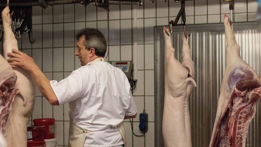 Vor der Verarbeitung wiegt Metzger Ralf Spindler die Schweinehälften. 