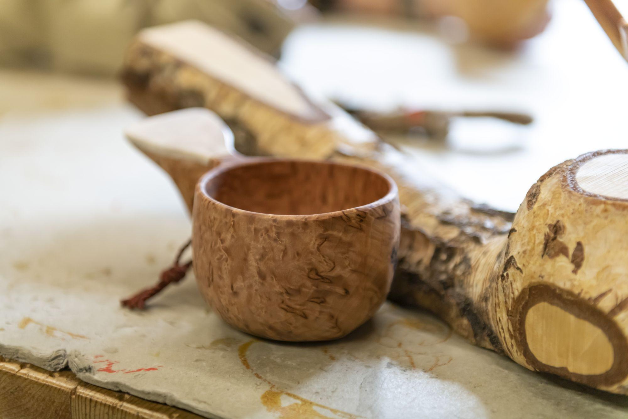 Aus bucklig gewachsenen Birken-Stämmen fertigen beide solche Trinkbecher an, Kuksa genannt. Viele Finnen nutzen diese reinen Naturprodukte beim Wandern. Die günstigere Variante nennt sich Kupilka und wird industriell aus recyceltem Holz und Plastik hergestellt. Beide Trinkbecher sind für Touristen ein beliebtes Mitbringsel.