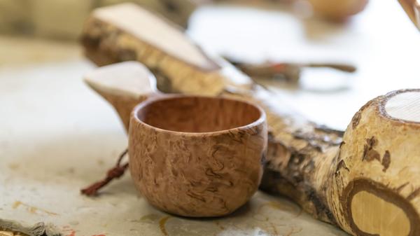Aus bucklig gewachsenen Birken-Stämmen fertigen beide solche Trinkbecher an, Kuksa genannt. Viele Finnen nutzen diese reinen Naturprodukte beim Wandern. Die günstigere Variante nennt sich Kupilka und wird industriell aus recyceltem Holz und Plastik hergestellt. Beide Trinkbecher sind für Touristen ein beliebtes Mitbringsel.