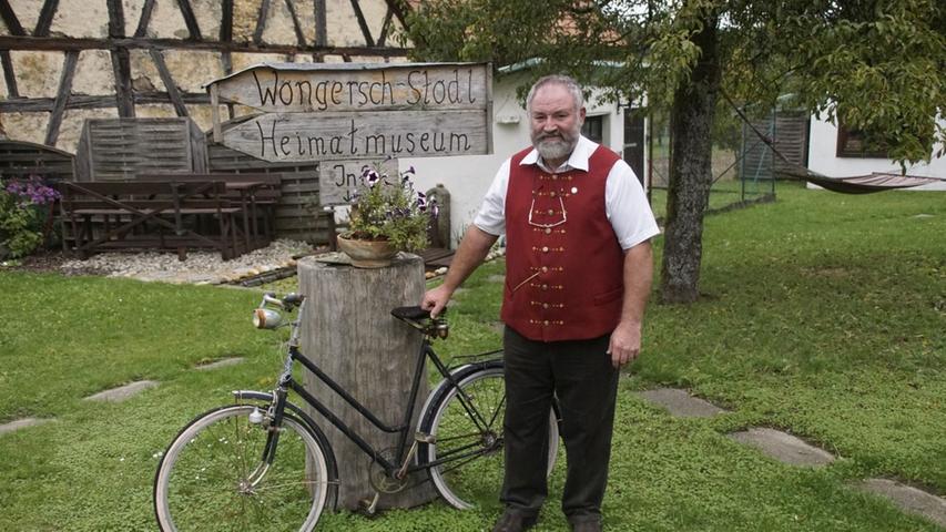 Robert Bogner steht vor dem Wegweiser im Garten, der zu seinem Wongersch-Stodl in Bieberbach zeigt. Der 52-Jährige trägt hier eine Tracht, die seine Frau geschneidert hat.