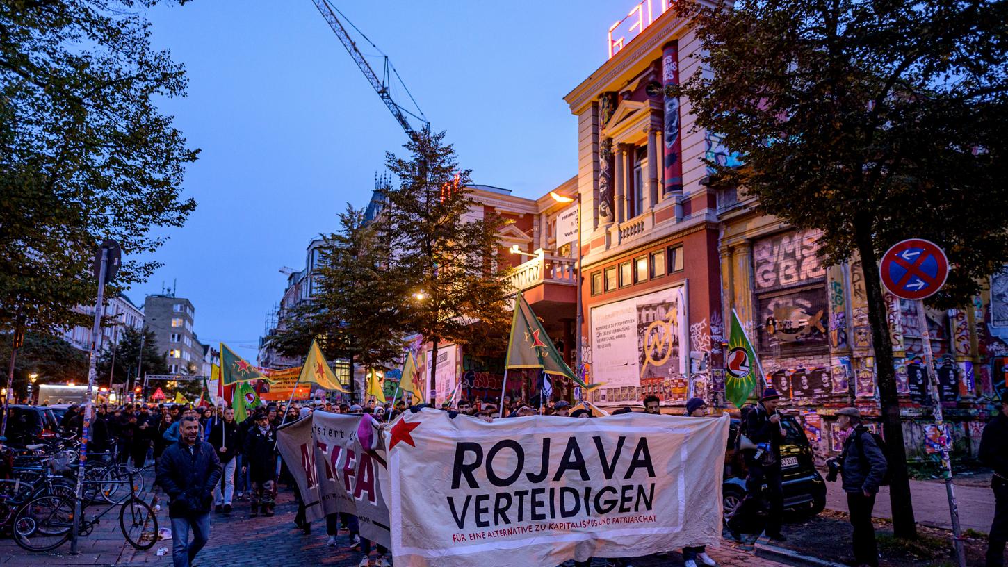 Kurden protestieren gegen vor der Roten Flora gegen die türkische Militäroffensive in Nordsyrien mit einem Banner mit der Aufschrift "Rojava verteidigen".
