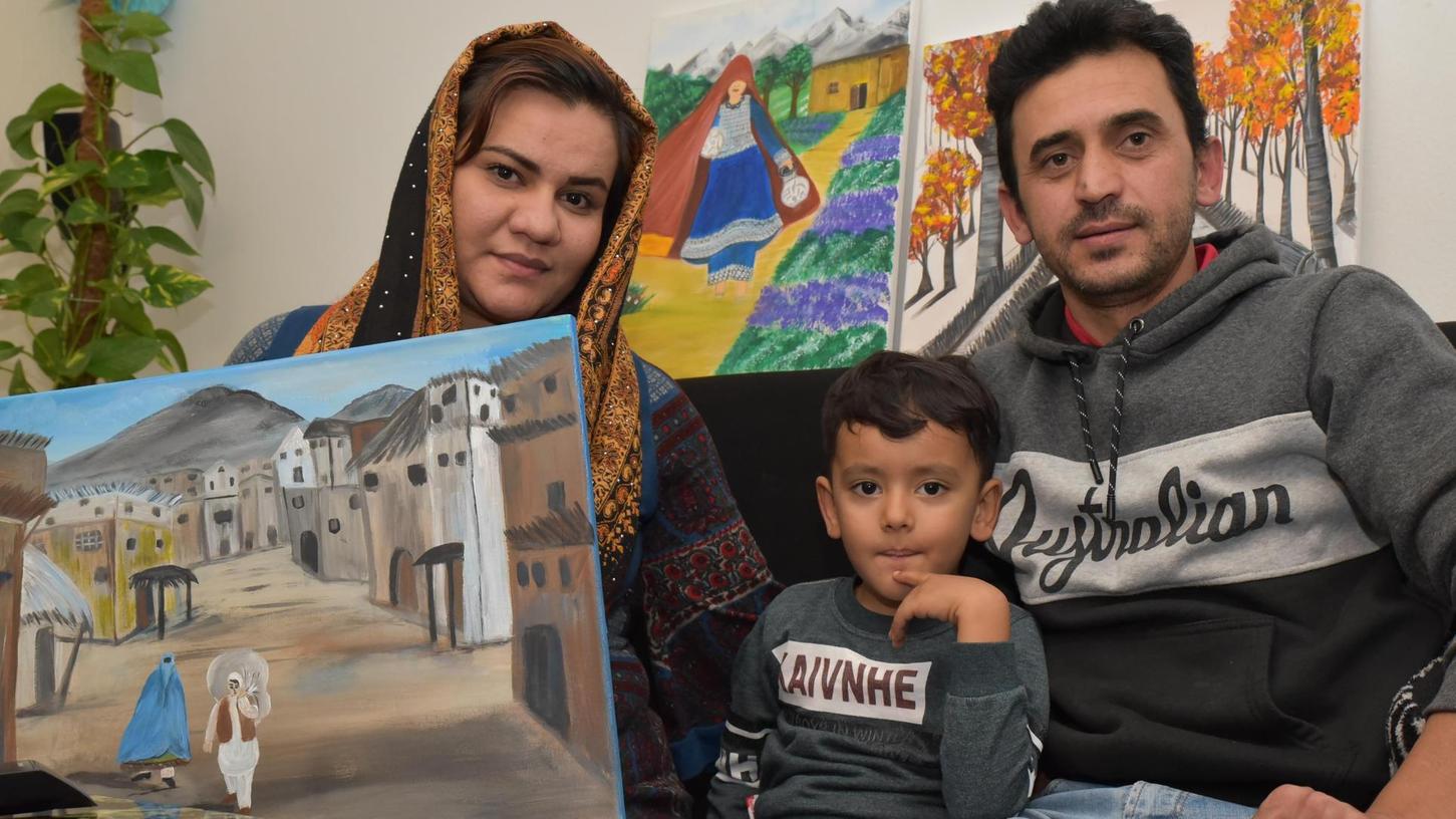 Nazireh Mohammadi mit Sohn Shahin und Ehemann Samad Sharifi sowie einem ihrer Bilder. Im Hintergrund sind weitere Gemälde zu sehen. Die afghanische Familie kam aus dem Iran nach Deutschland, in Shiraz galten sie als unerwünschte Ausländer und durften nur niedere Tätigkeiten verrichten.