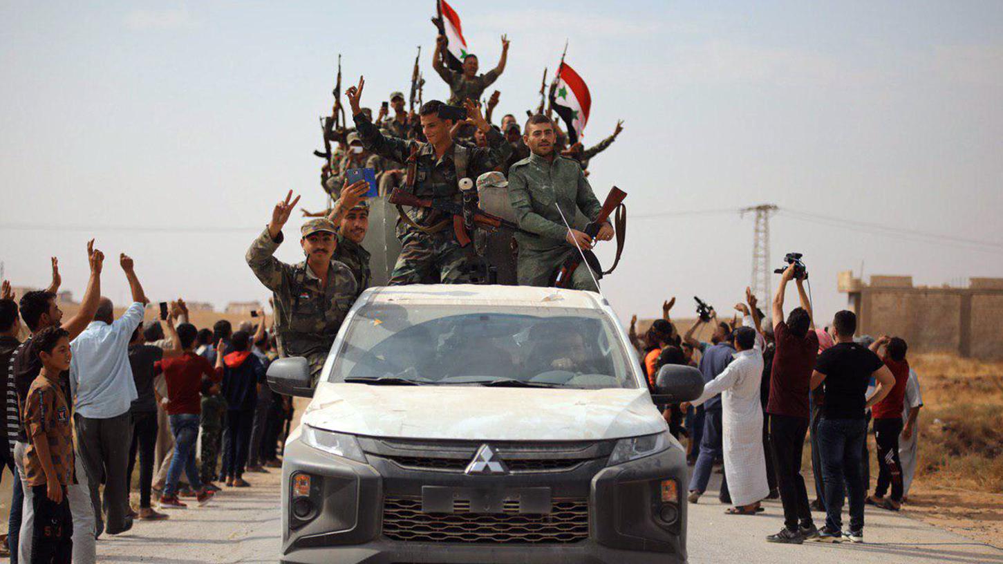 Syrische Regierungstruppen schwenken Nationalfahnen, während sie in die nördliche Stadt Ain Issa fahren. Syrische Regierungstruppen wurden am Montag nach einem Abkommen zwischen den Kurden und Damaskus zu den kurdischen Hochburgen im Nordosten Syriens verlegt. Syrische Regierungstruppen schwenken Nationalfahnen, während sie in die nördliche Stadt Ain Issa fahren. Syrische Regierungstruppen wurden am Montag nach einem Abkommen zwischen den Kurden und Damaskus zu den kurdischen Hochburgen im Nordosten Syriens verlegt.
