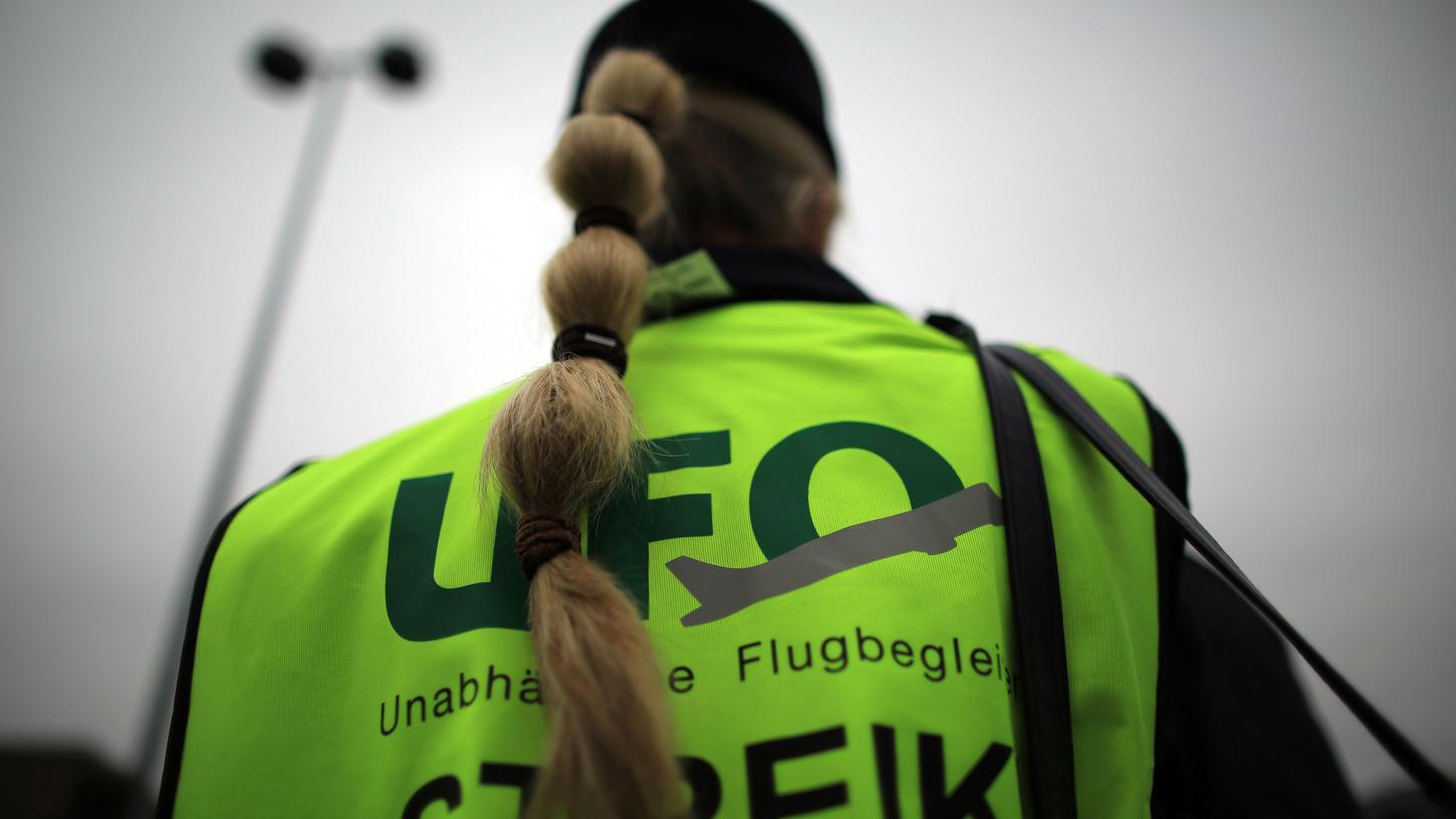 Eine Flugbegleiterin steht vor dem Unternehmenssitz von Eurowings bei einer Kundgebung.
