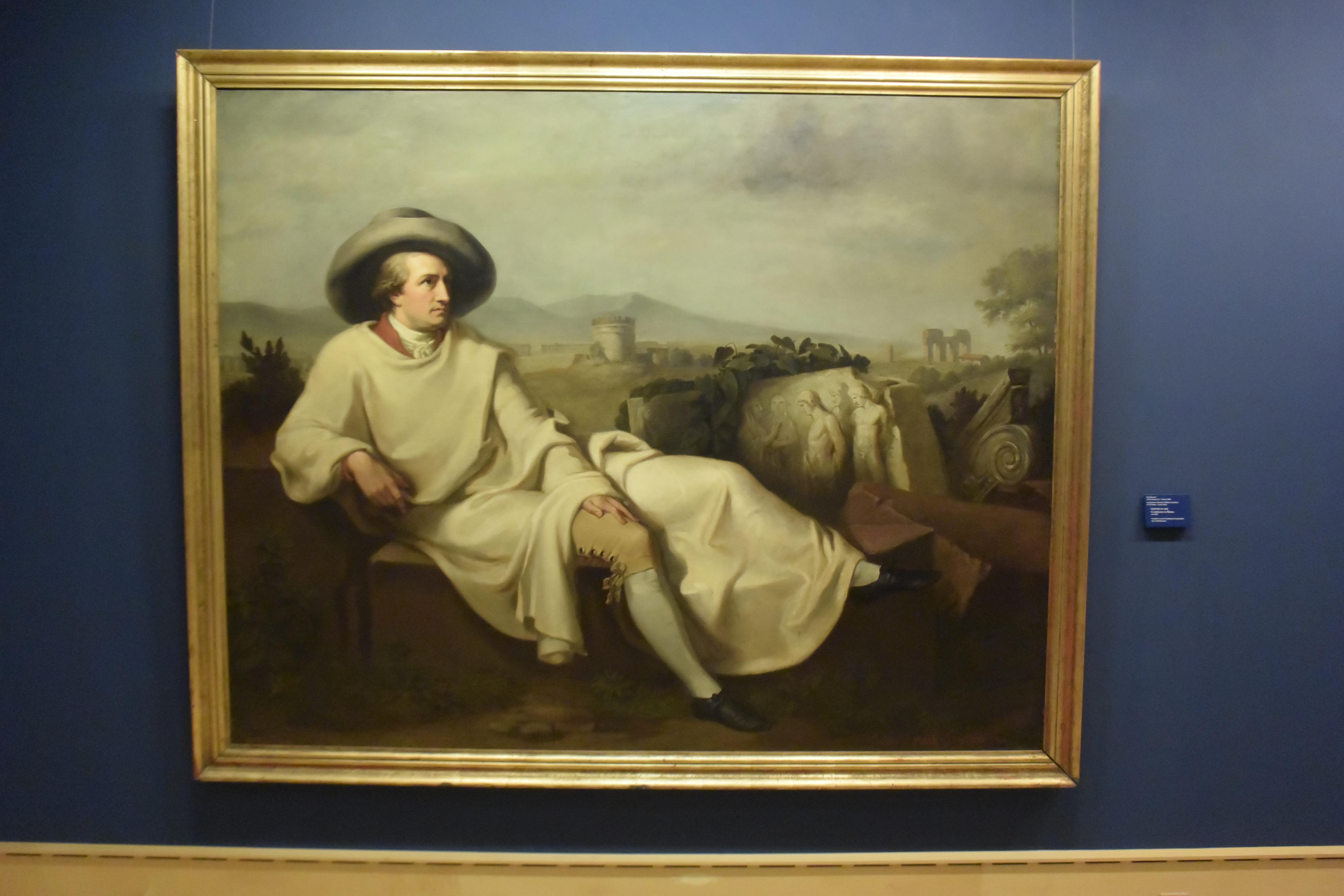 In einen Reisemantel gehüllt, lagert Goethe umgeben von Zeugnissen der Antike. Das ausdrucksstarke Dreiviertelprofil überragt die Komposition. Der sinnende Blick des Dichters geht in die Ferne.