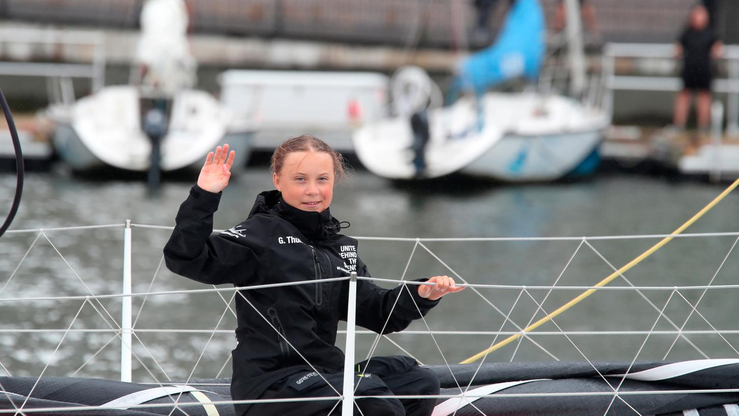 Greta Thunberg, die 16-jährige schwedische Klimaaktivistin, winkt an Bord der Malizia II bei der Fahrt in den Hafen. Weniger als drei Wochen vor dem Beginn der nach Madrid verlegten Weltklimakonferenz hat Thunberg eine Rückreisemöglichkeit über den Atlantik gefunden.