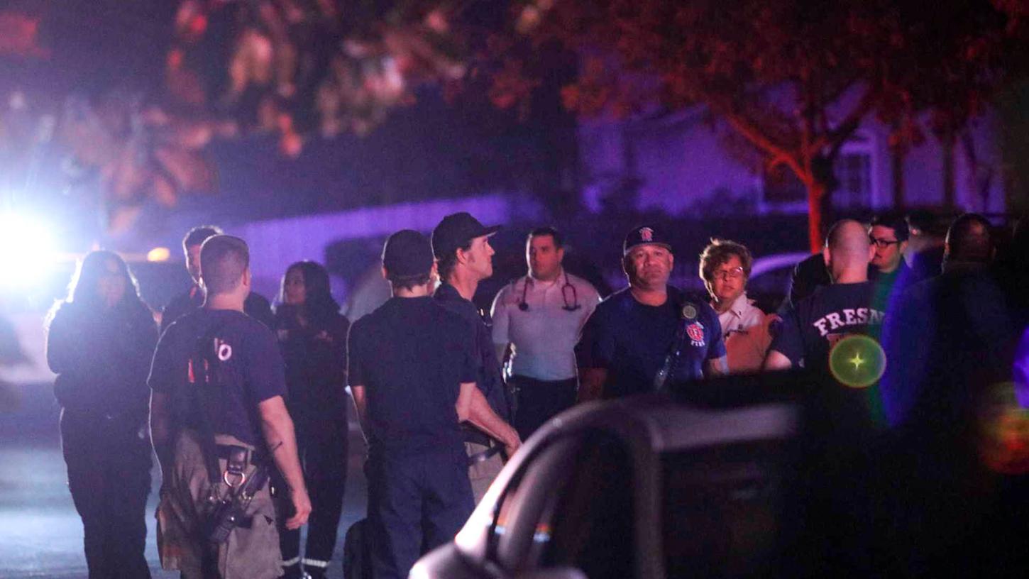Einsatzkräfte von Polizei und Feuerwehr stehen auf einer Straße. Vier Menschen sind im US-Staat Kalifornien in einem Garten von einem Unbekannten erschossen worden.