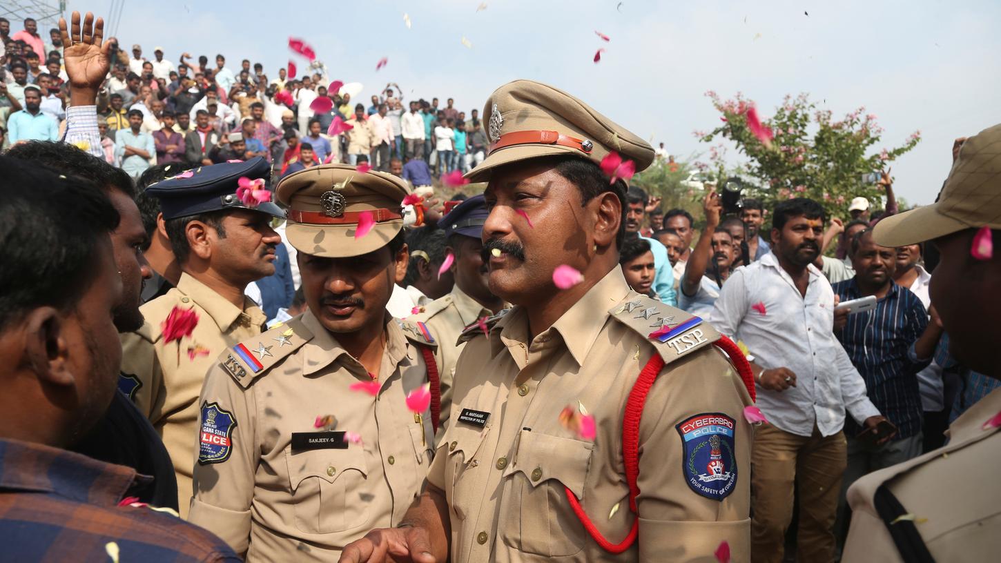 Menschen werfen Blütenblätter auf indische Polizisten, nachdem diese vier mutmaßliche Vergewaltiger erschossen hatten.