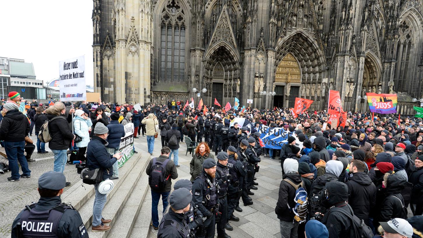 Demonstranten der AfD (links) und von "Köln gegen rechts" stehen einander auf dem Domvorplatz gegenüber, während die Polizei die Lager trennt.
