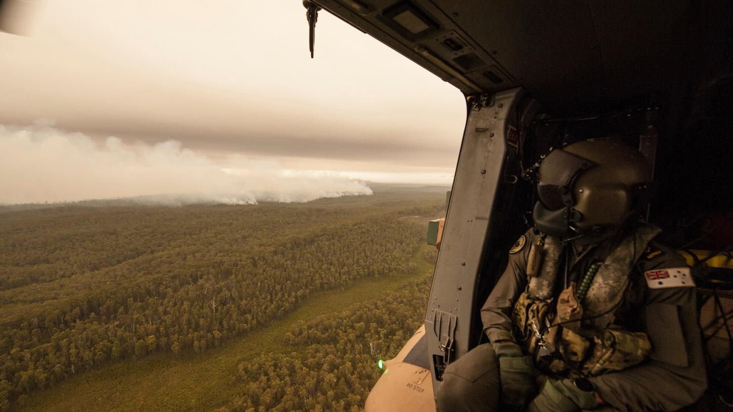 Ein Militärhubschrauber fliegt über einen Buschbrand bei Cann River. In den Bundesstaaten New South Wales und Victoria loderten noch mehr als 180 Feuer.