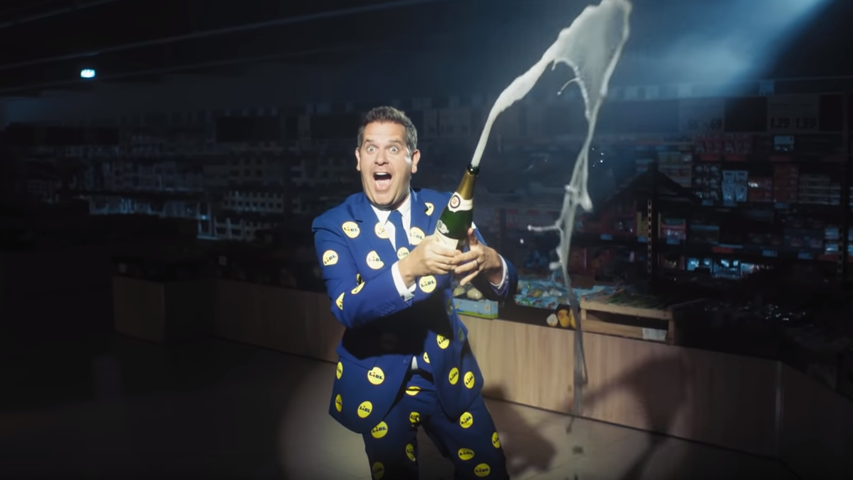 Peter Wackel wirbt Champagner spritzend für den Discounter Lidl. Das Video wurde in einer Filiale in Berlin aufgenommen.