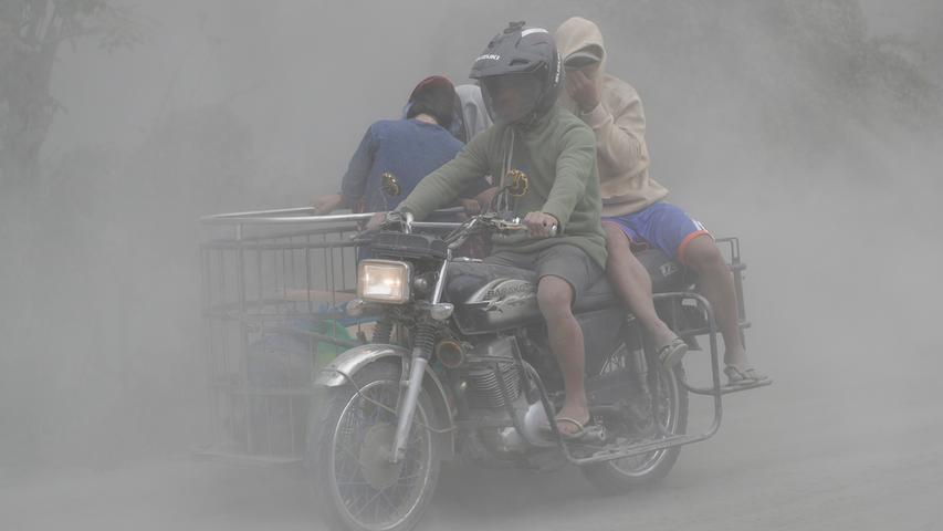 Die Philippinen im Ausnahmezustand: Eine Familie fährt während des Ausbruchs des Vulkans "Taal" in Tagaytay in der südlichen Provinz Cavite auf einem Motorrad durch eine Aschewolken. Auf den Philippinen könnte der gefährliche Vulkan Hunderttausende Menschen in die Flucht treiben. Aus dem nahe der Hauptstadt Manila gelegenen Vulkan "Taal" ergoss sich Lava.