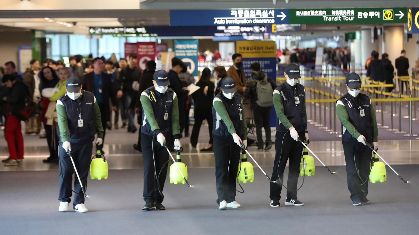 Flughafenpersonal sprüht in der Ankunftshalle am internationalen Flughafen Incheon in Südkorea als Schutzmaßnahme gegen die Verbreitung des Corona-Virus eine keimtötende Lösung.