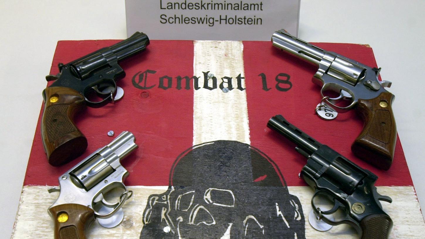 Sichergestellte Waffen und ein Schild der kriminellen Neonazi-Gruppe "Combat 18" liegen im schleswig-holsteinischen Landeskriminalamt.