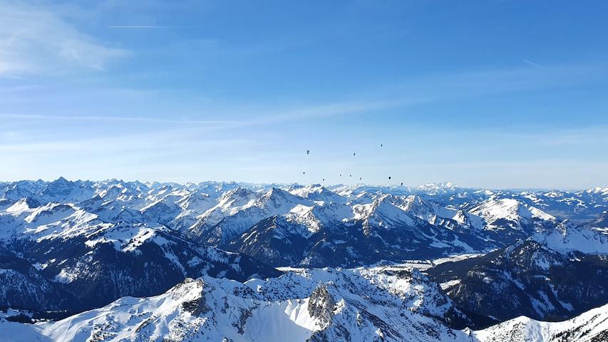 Alpenpanorama mit winzigen Punkten am Horizont: die restlichen Ballons sind inzwischen nur noch in weiter Ferne zu erkennen.