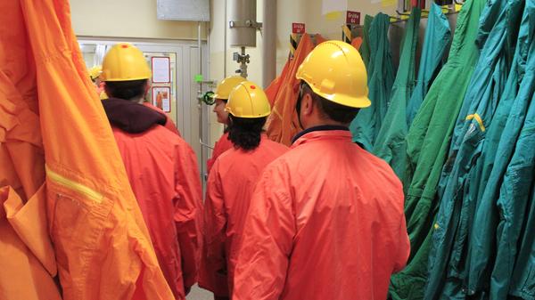 Wer das Kernkraftwerk in Grafenrheinfeld betreten will, muss Schutzkleidung tragen. Die Arbeiter stecken in orangefarbenen Kitteln, der Strahlenschutz in grünen. Besuchergruppen bekommen rote Mäntel und Überschuhe. In der Brusttasche misst ein Dosimeter die Strahlenbelastung während des Besuchs.