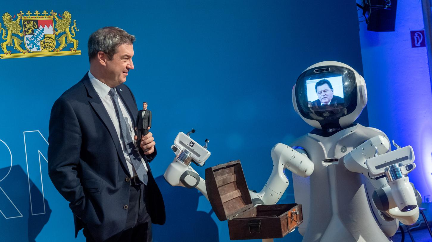 Markus Söder hält bei einer Diskussionsveranstaltung zur Hightech-Agenda Bayern eine Mini-Version seiner selbst in der Hand. Markus Söder hält bei einer Diskussionsveranstaltung zur Hightech-Agenda Bayern eine Mini-Version seiner selbst in der Hand.